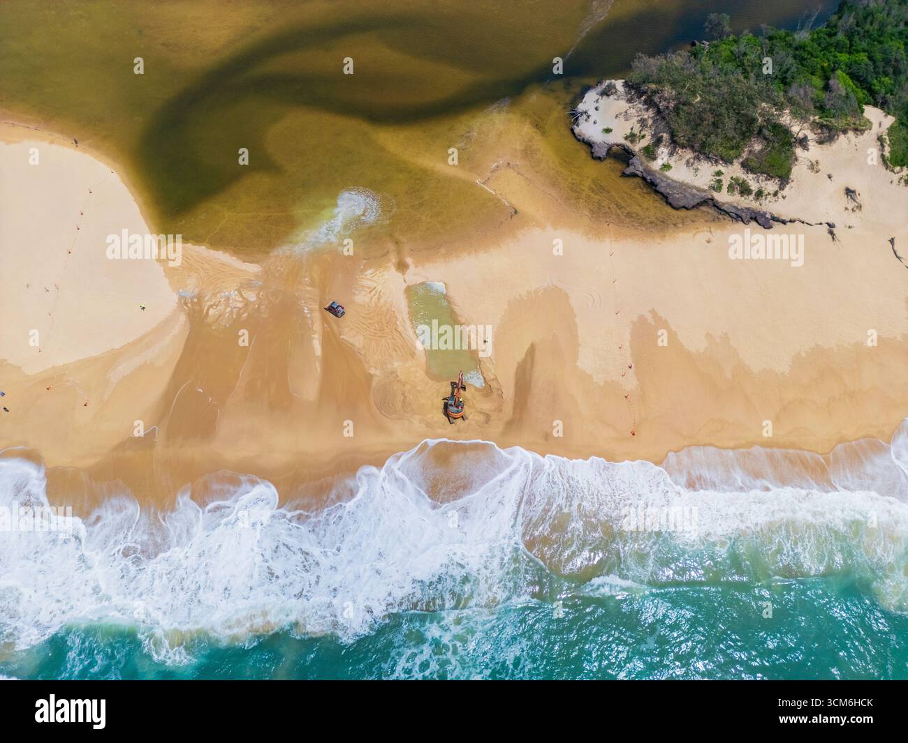 Vue aérienne d'engins de terrassement ouvrant un canal d'eau d'un lac à l'océan à Currimundi sur le Sunshine Caost dans le Queensland, Australie Banque D'Images
