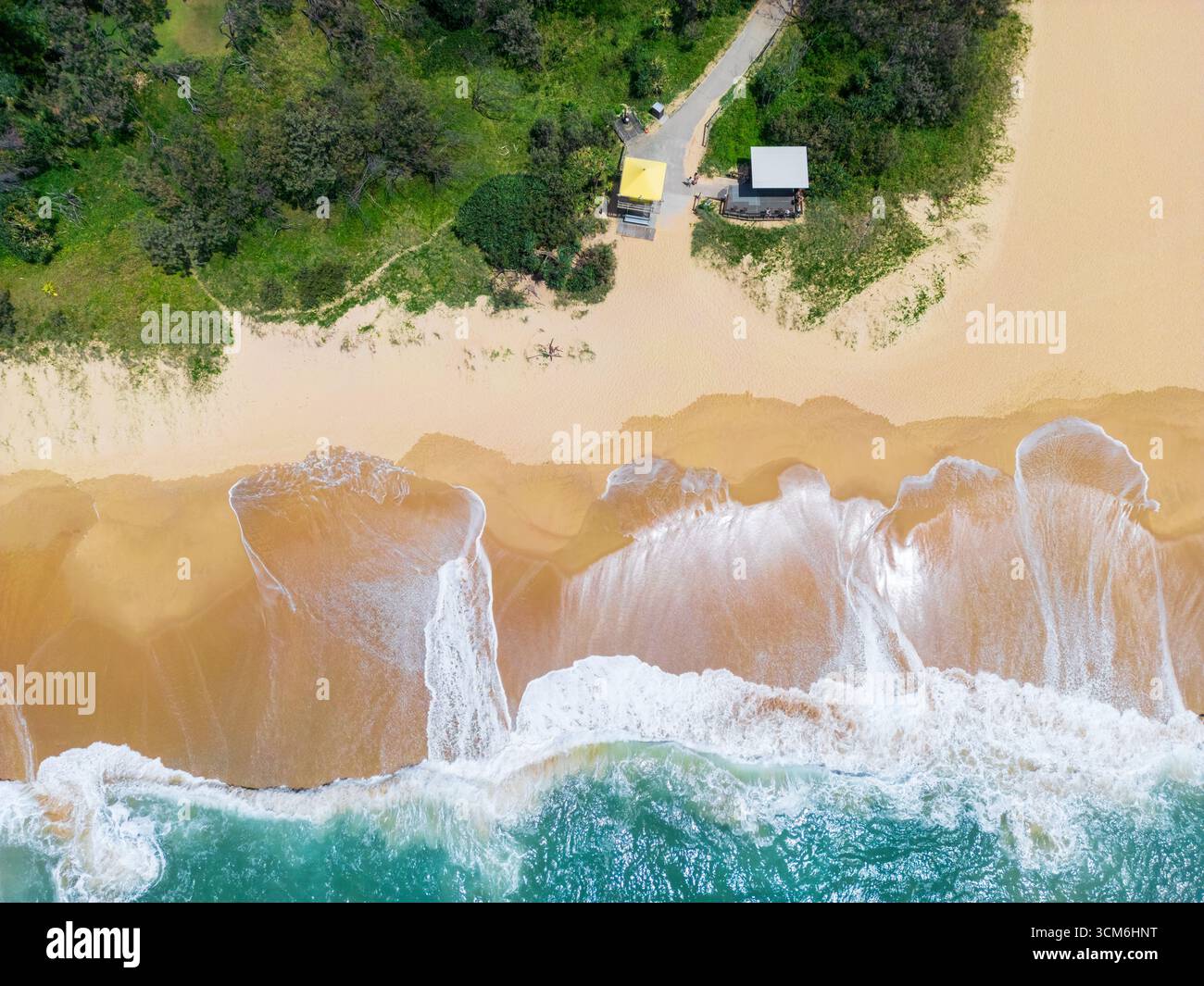 Vue aérienne des vagues sur une plage de sable sous une tour de sauveteurs à Currimundi sur la Sunshine Coast dans le Queensland, Australie. Banque D'Images