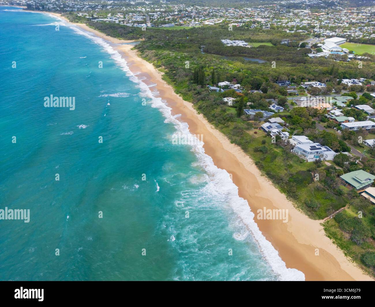 Vue aérienne d'un logement niché dans la végétation côtière derrière une longue plage de sable à Currimundi sur la Sunshine Coast dans le Queensland, Australie. Banque D'Images
