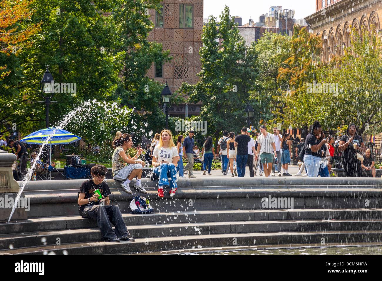 New York City, New York - 6 septembre 2025 : les gens visitent et apprécient le Washington Square Park autour de la fontaine. Banque D'Images