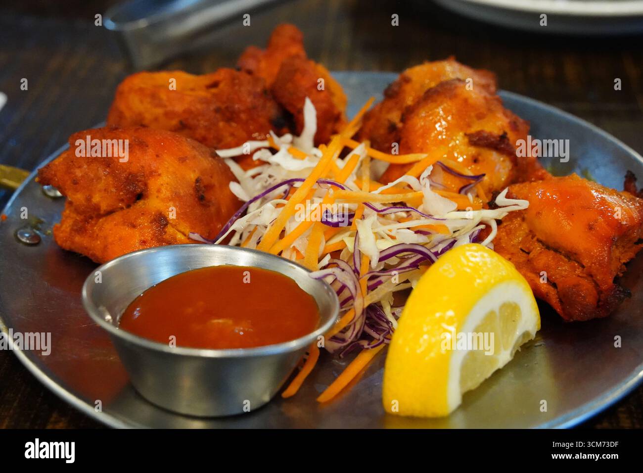 Poulet indien Tikka servi avec citron et salade Banque D'Images