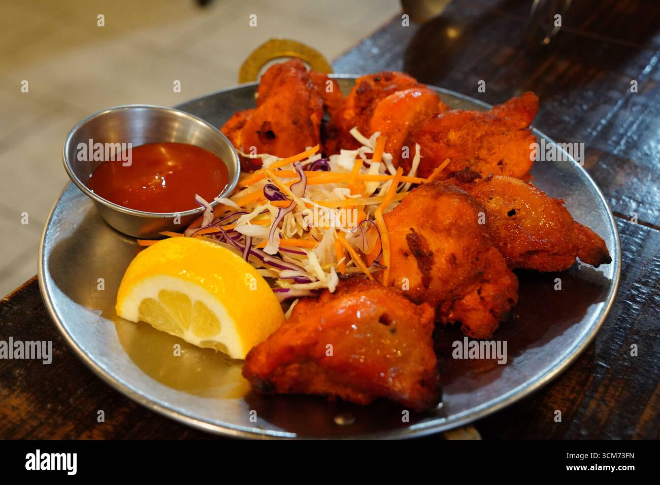 Poulet indien Tikka servi avec citron et salade Banque D'Images
