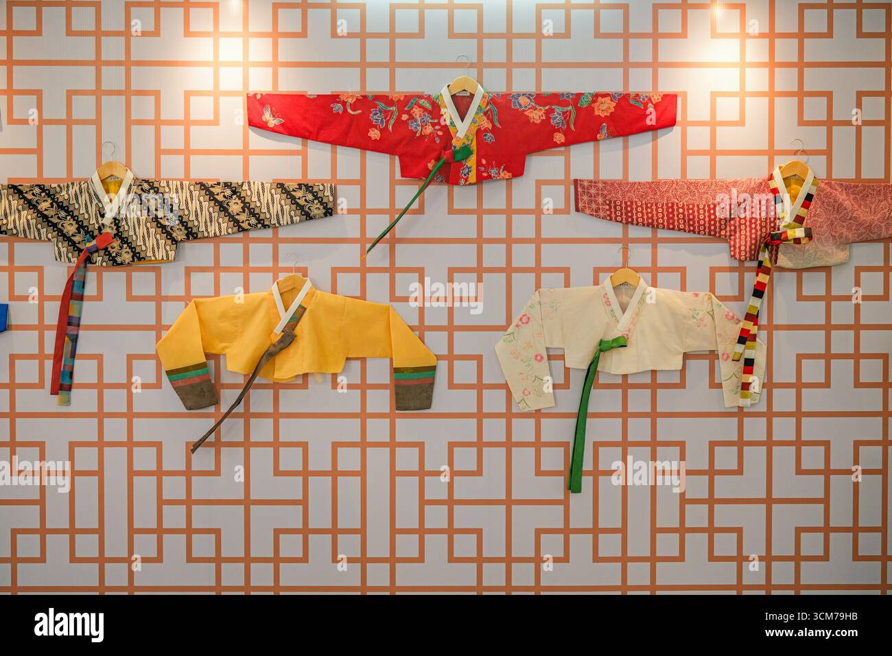 Présentation de vestes traditionnelles de hanbok coréennes disposées sur un mur à motifs Banque D'Images