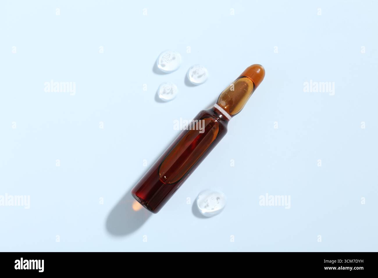 Ampoule en verre avec produit cosmétique sur fond bleu clair, vue de dessus Banque D'Images