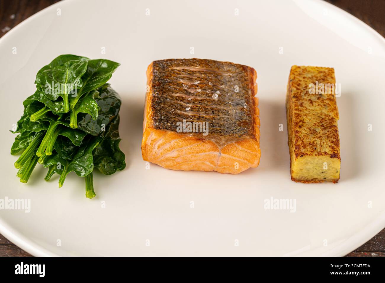 Filet de saumon poêlé servi avec épinards fanés et croquette de pommes de terre Banque D'Images