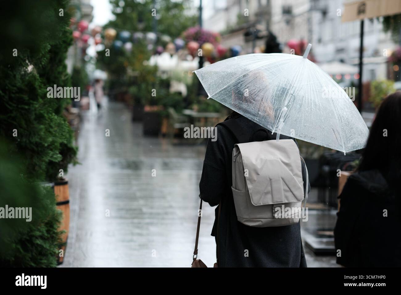 Personne avec parapluie transparent marchant sur la rue Piotrkowska pluvieuse à Lodz, Pologne, symbole du mode de vie urbain et de la météo Banque D'Images