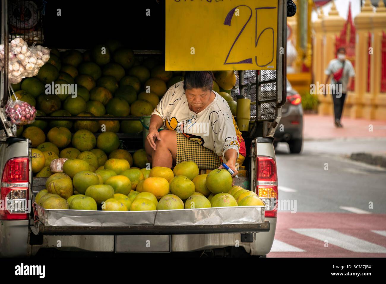 Bangkok, Thaïlande, 6 septembre 2025 : une vendeuse de rue vend des pomelos à l'arrière de son camion avec une pancarte indiquant le prix de 25 bahts. Banque D'Images