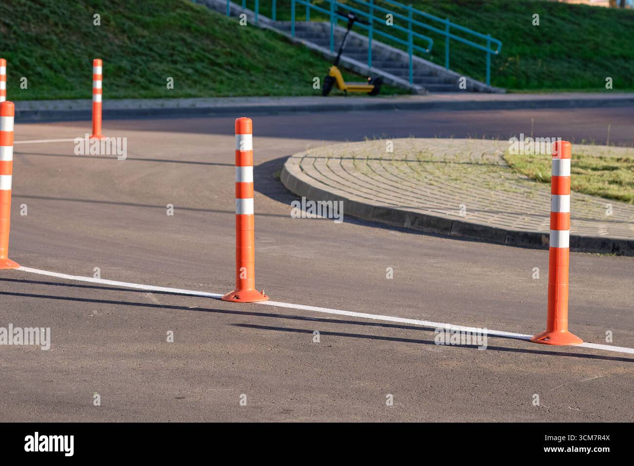 Des cônes orange vif bordent le bord d'un sentier, guidant les piétons en toute sécurité le long d'un itinéraire bien entretenu à côté d'une zone herbeuse sous un bleu clair Banque D'Images