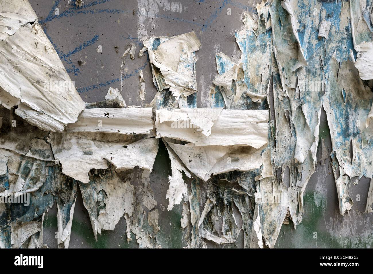Vieux poster déchiré déchiquette sur un mur sale créant un fond texturé grunge et un motif urbain. Banque D'Images