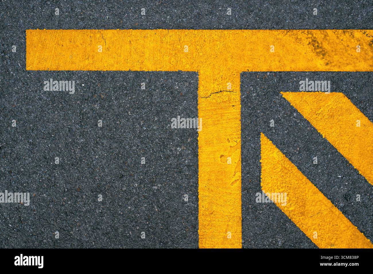 Lignes jaunes géométriques peintes sur la route asphaltée, fond de motif urbain abstrait. Vue de dessus. Banque D'Images