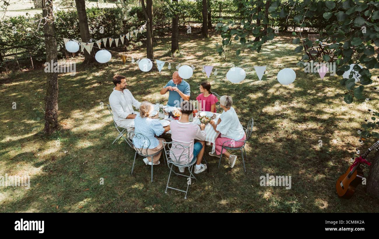 Vue imprenable sur les grands-parents, les parents et les enfants dînant ensemble à l'extérieur, soirée grill le week-end. Banque D'Images