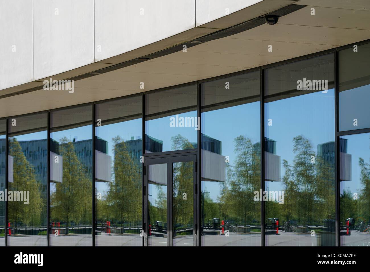 Danemark, Copenhague. La Royal Arena présente des panneaux de verre réfléchissants qui reflètent le mouvement et la lumière de la ville. Les reflets changeants des bâtiments, des arbres et des saisons transforment sa façade en une symphonie urbaine dynamique. Banque D'Images