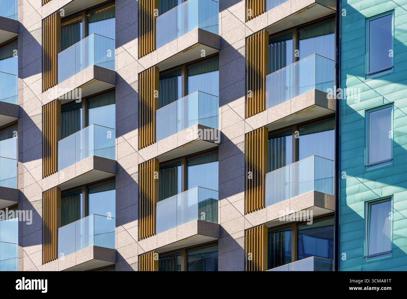 Lignes géométriques épurées : une touche d'élégance. Conçu par Mellbye Architects, l'hôtel Thief de Tjuvholmen à Oslo, en Norvège, présente une façade de verre et de nervures métalliques à côté de murs aux tons aqua, reflétant la transformation de la région en front de mer urbain dynamique. Banque D'Images