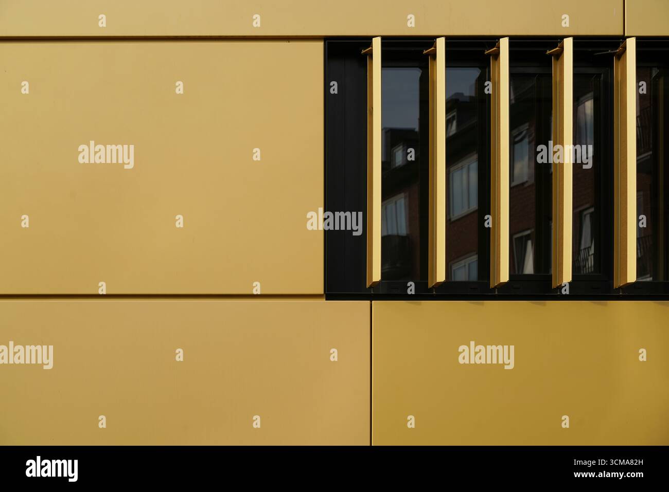 Ouverture artistique : un aperçu de l'innovation et de l'harmonie. Le siège de AachenMünchener à Aix-la-Chapelle, en Allemagne, conçu par kadawittfeldarchitektur, présente des panneaux dorés et des fenêtres réfléchissantes qui fusionnent l’esthétique moderne et les reflets urbains. Banque D'Images