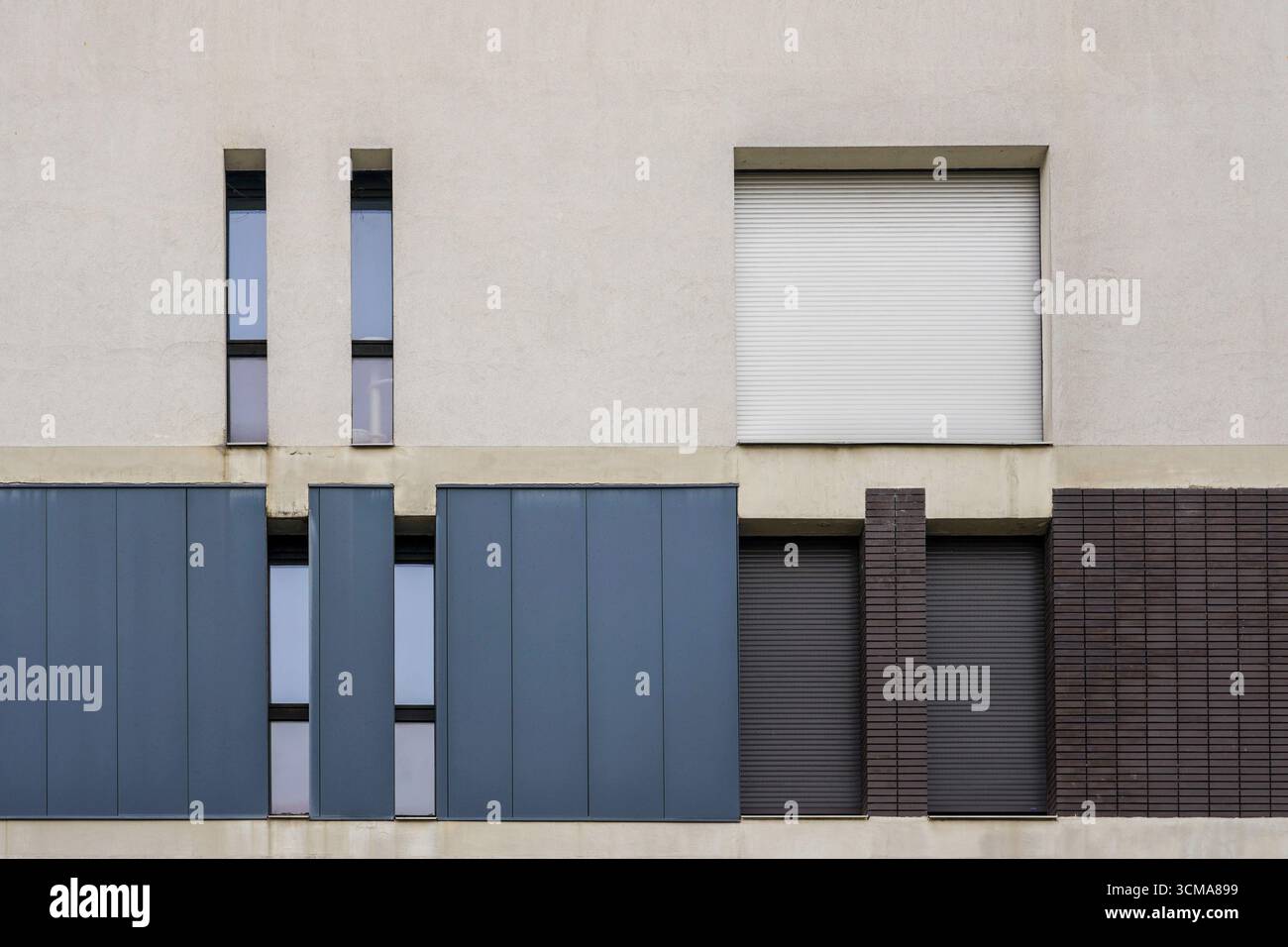 Composition de façade : une approche minimaliste. La façade d'un bâtiment à Grenoble, France, montre une composition d'éléments verticaux et horizontaux. Différentes tailles de fenêtre et une palette de couleurs discrètes créent rythme et simplicité dans un design moderne. Banque D'Images