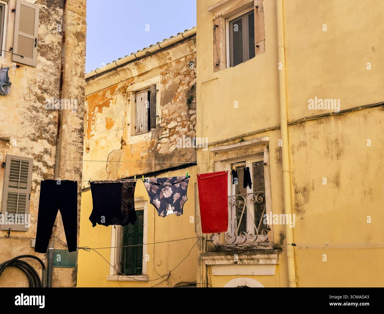La buanderie est suspendue au-dessus de l'étroite ruelle dans la vieille ville de Corfou, en Grèce. Bâtiments d'architecture traditionnelle. Scène de rue méditerranéenne Banque D'Images