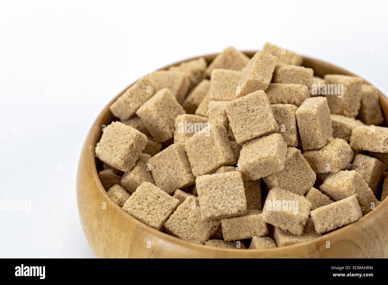 Un sucre brun bio cubes dans un bol en bois isolé sur fond blanc édulcorant naturel ingrédient sain cuisine rustique close up concept cle alimentaire Banque D'Images
