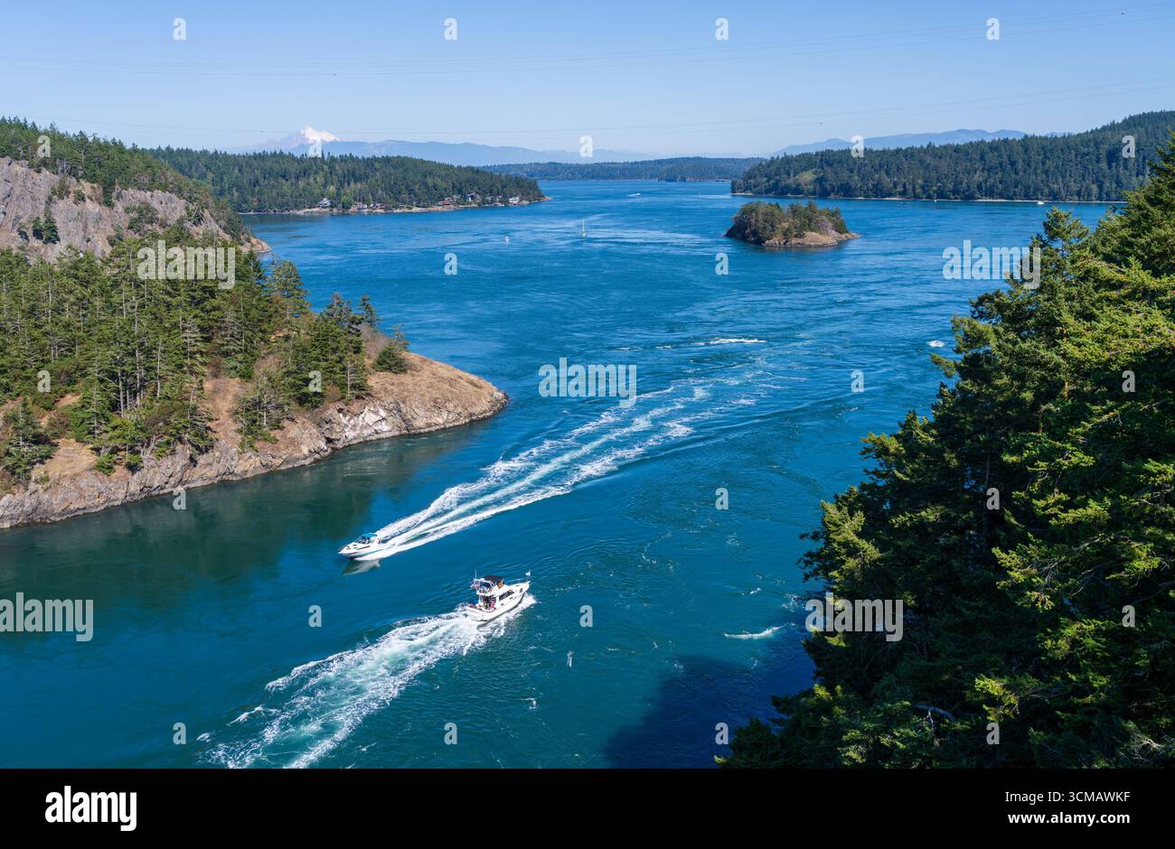 Bateaux passant dans les eaux turbulentes de Deception Pass dans la baie de Skagit avec Mt Baker dans la distance vue depuis le pont Banque D'Images