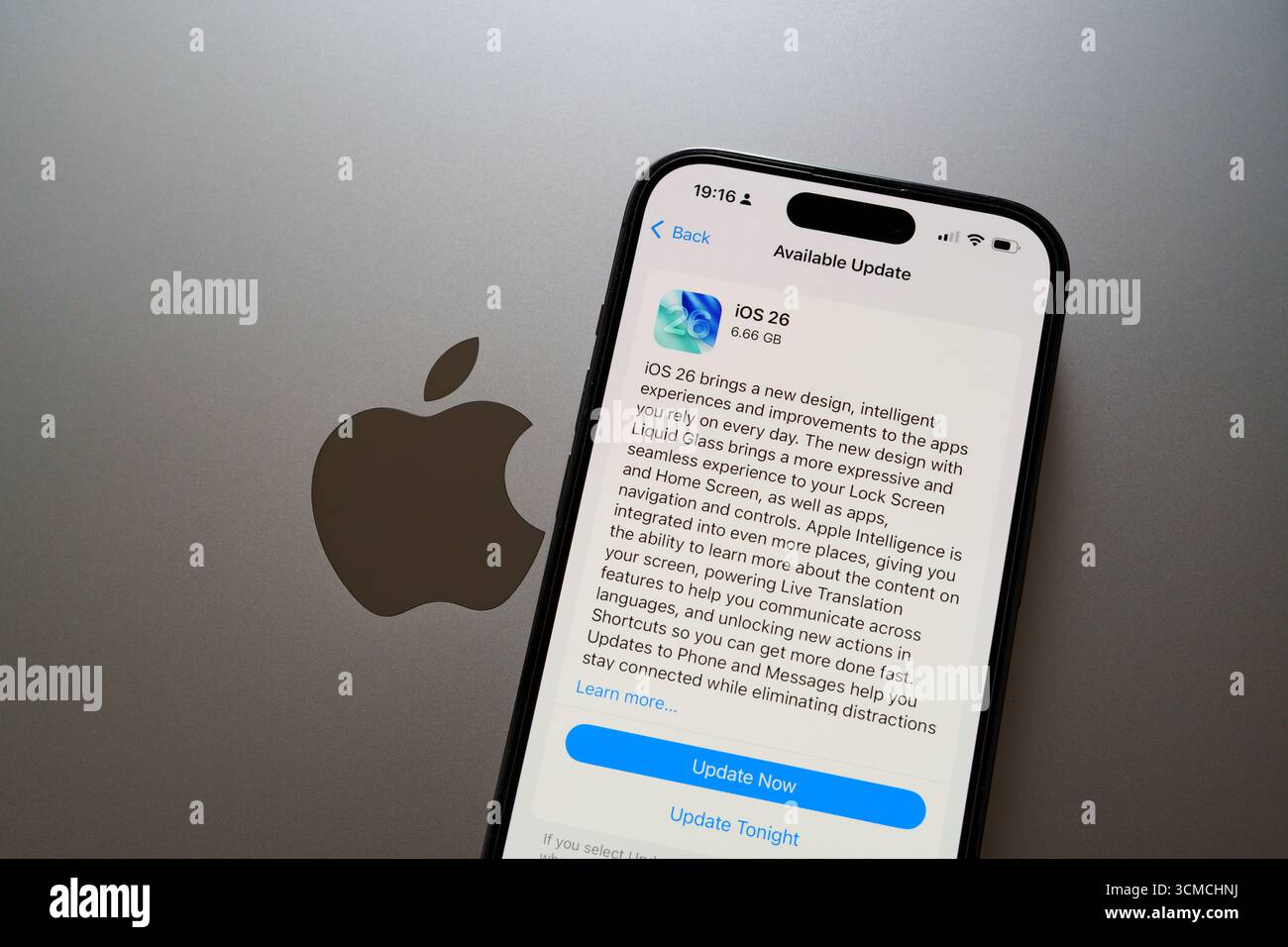 Mise à jour iOS 26 sur iPhone à côté du logo Apple sur MacBook en mode lumière. Stafford, Royaume-Uni, 15 septembre 2025 Banque D'Images