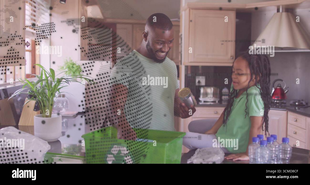 Trier le père et la fille en plaçant les matières recyclables sur le comptoir de la cuisine de la maison, avec un bac de recyclage vert Banque D'Images