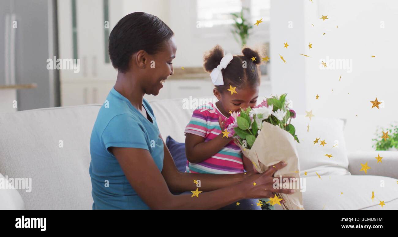 Mère et fille sentant des fleurs roses et blanches enveloppées de papier sur un canapé gris clair dans le salon Banque D'Images