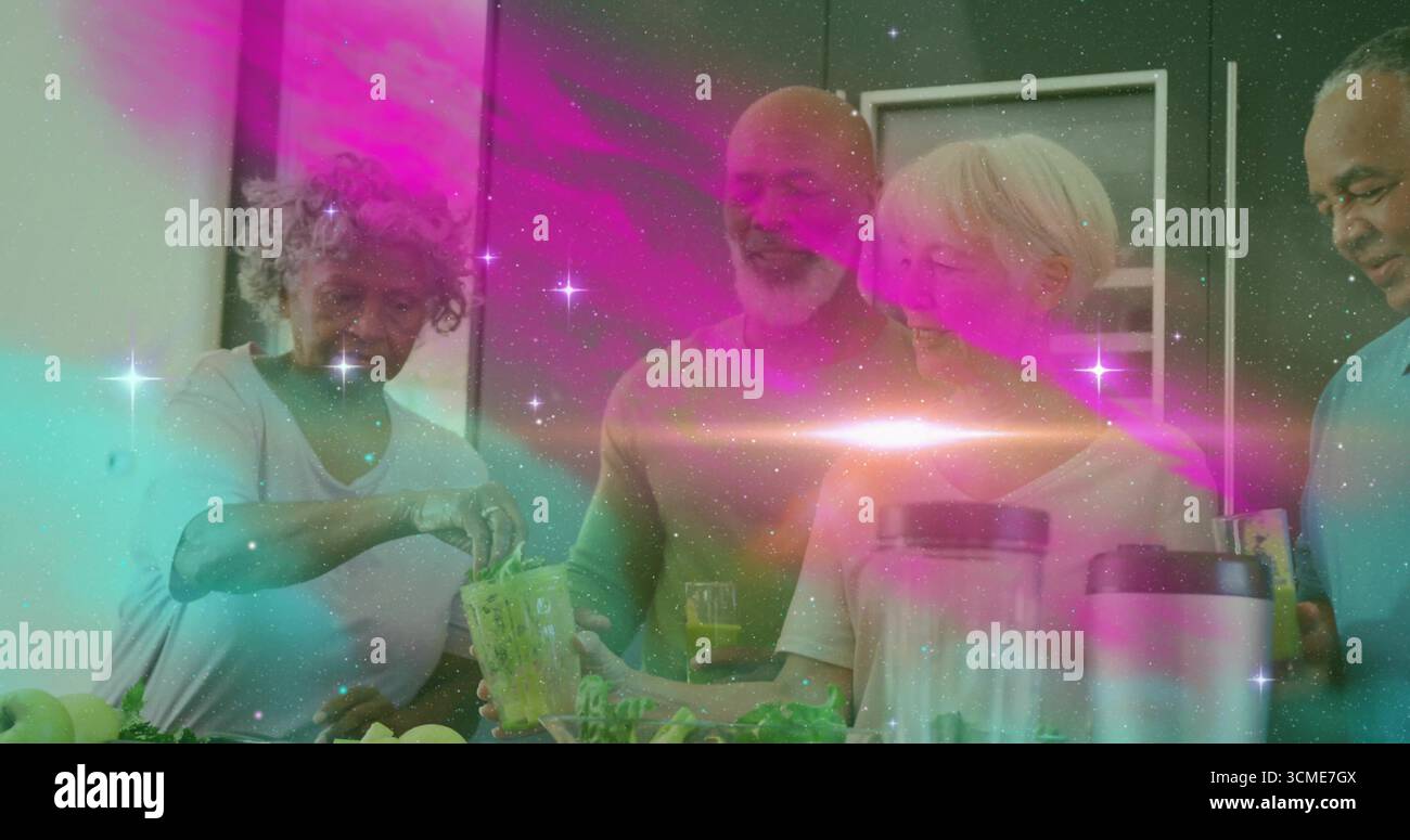 Groupe d'amis mélangeant et versant des smoothies verts frais à l'îlot de cuisine, avec des verres à jus Banque D'Images