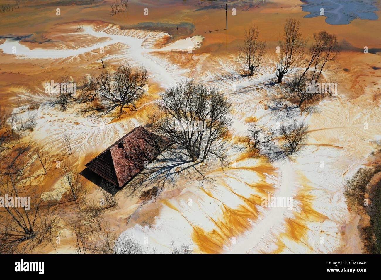 Vue aérienne de la maison de village en train de couler au milieu de l'étang de décantation de drainage de mine acide toxique. Geamana, Rosia Montana, Roumanie Banque D'Images