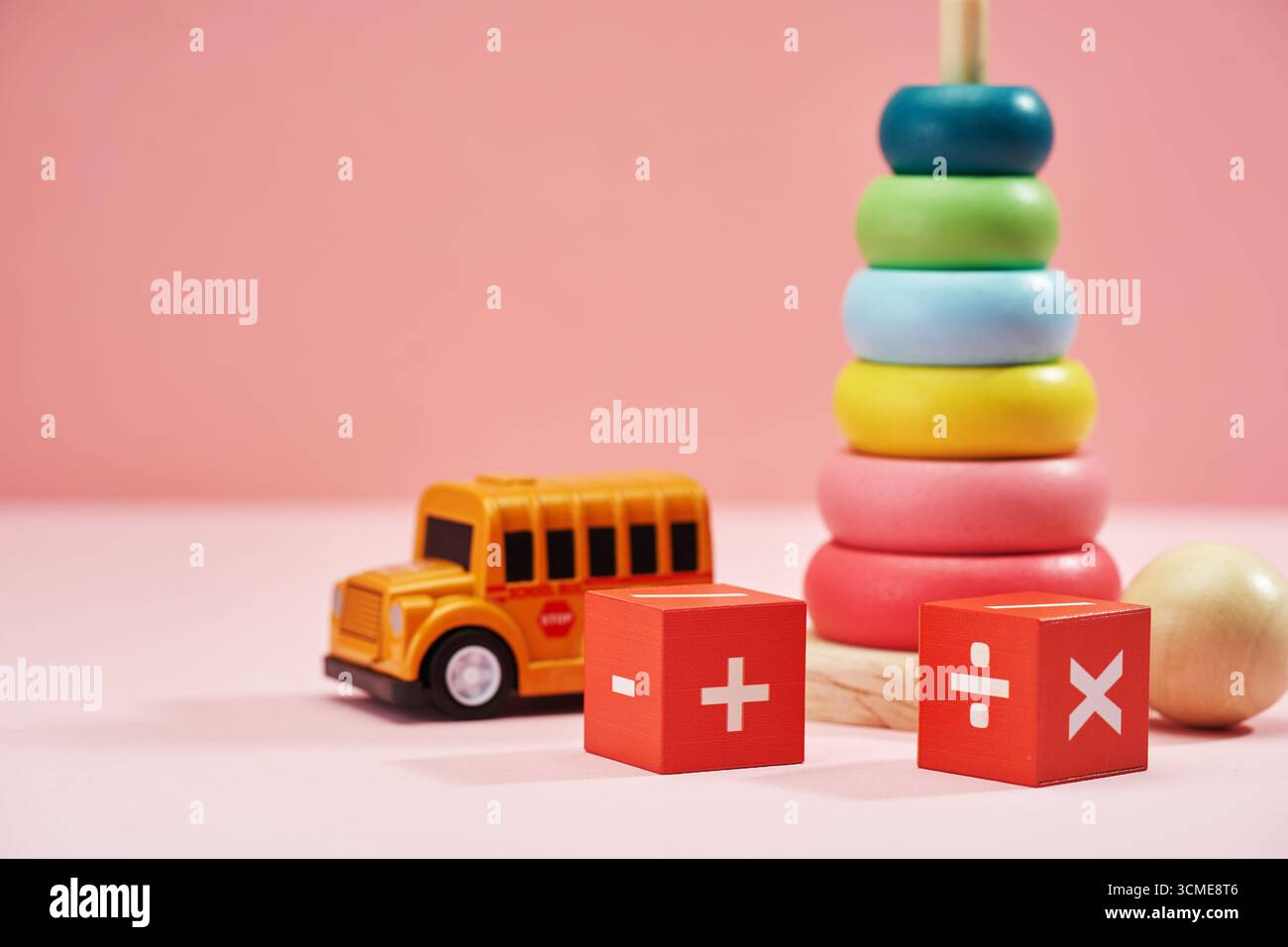 jouets pour bébés, autobus scolaire jouet et symbole mathématique sur fond rose Banque D'Images