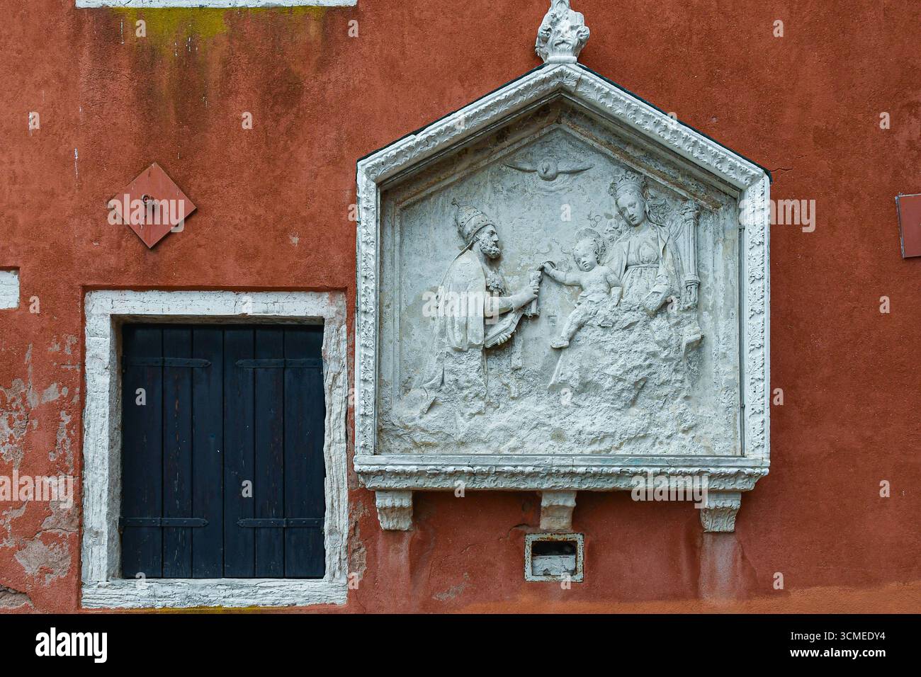Gros plan d'un sanctuaire votif avec un bas-relief représentant la Vierge et l'enfant intronisés avec Saint Pierre (XVe siècle), San Pietro di Castello, Venise Banque D'Images