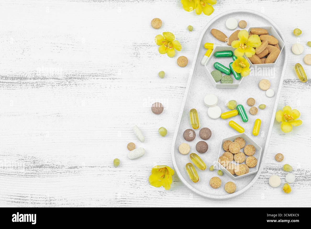 Compléments alimentaires assortis, vitamines et capsules de phytothérapie avec fleurs de molène fraîche (Verbascum) sur un fond de bois blanc, soins de santé a Banque D'Images