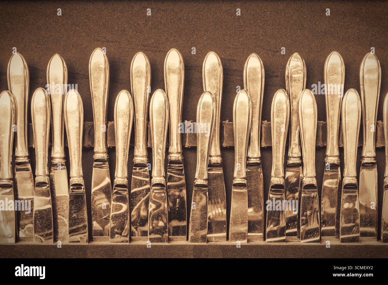Image de style rétro d'une grande collection de couteaux de table en argent antique Banque D'Images