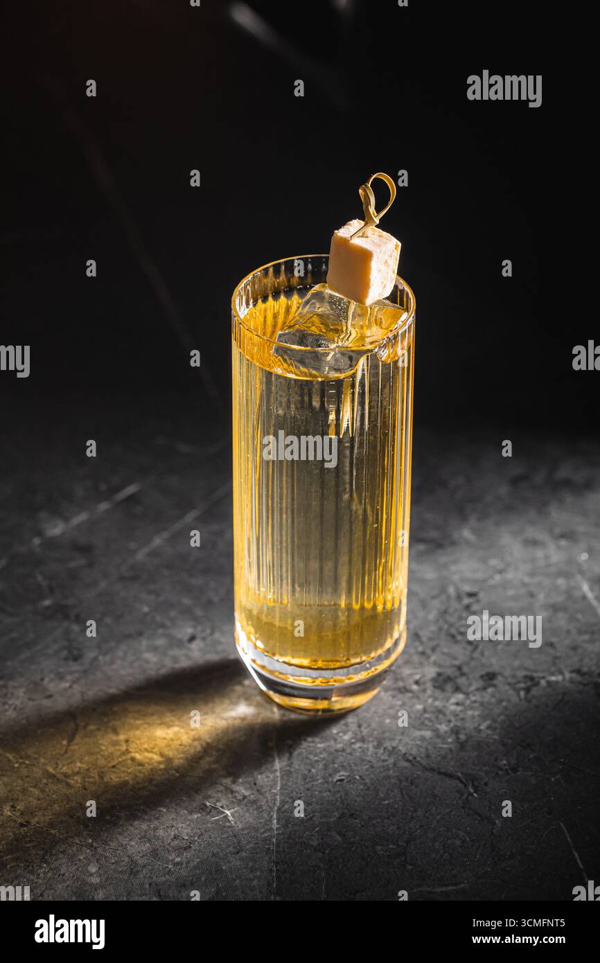Cocktail highball avec glaçon et lueur dorée Banque D'Images