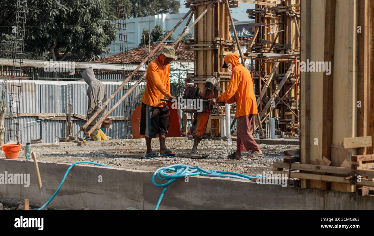 Un ouvrier de la construction utilise une machine de compacteur de sol pour renforcer la base du sol, une étape essentielle dans la préparation du site pour des structures stables. Banque D'Images