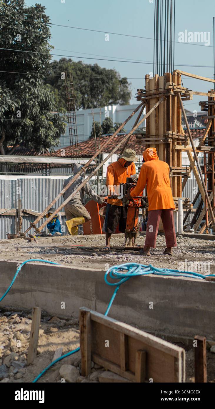 Un ouvrier de la construction utilise une machine de compacteur de sol pour renforcer la base du sol, une étape essentielle dans la préparation du site pour des structures stables. Banque D'Images