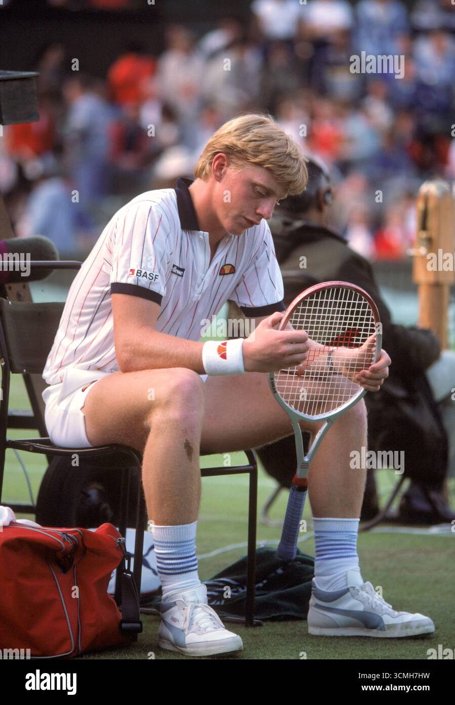 Boris Becker jouant au club de tennis de Wimbledon Lawn quand il avait 17 ans adolescent. Assis entre les sets, regardant la raquette de tennis. En dehors des courts, il concourt pour remporter la finale du tournoi Mens Singles. Chaussures PUMA sur chemise logo BASF parrainage d'entreprise 7 juillet 1985 1980s UK HOMER SYKES Banque D'Images