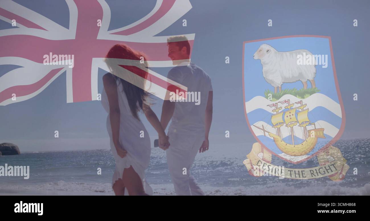 Couple marchant en blanc tenant les mains touchant les vagues de la plage, avec drapeau national fané, blason Banque D'Images