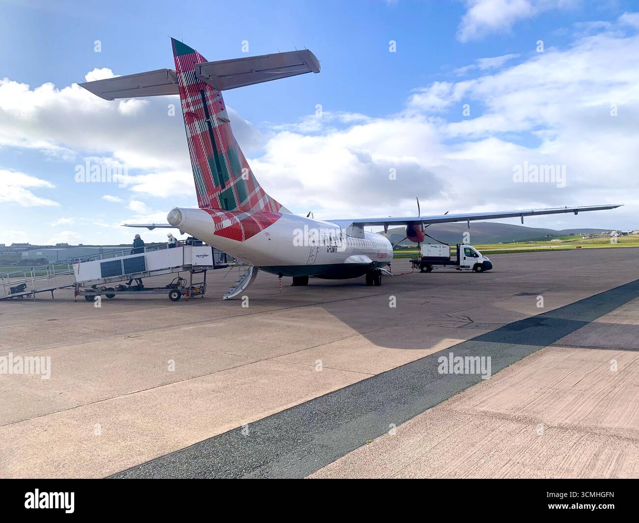 Îles Shetland aéroport piste avion atterrissage Lerwick queue route collines panneau routier Agneau mouton eau mer bruyère montagnes Aéroport Logan Air - Image de stock capturée avec un smartphone