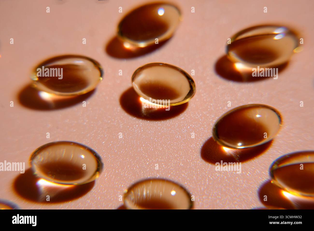 Plusieurs capsules de vitamine d dorée créent des ombres sur un fond rose, favorisant la santé et le bien-être Banque D'Images