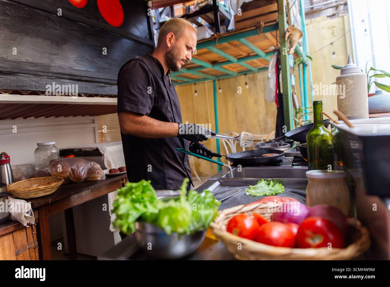 Le chef cuisinier grillera parfaitement des patties de bœuf fraîches pour un hamburger ultime Banque D'Images