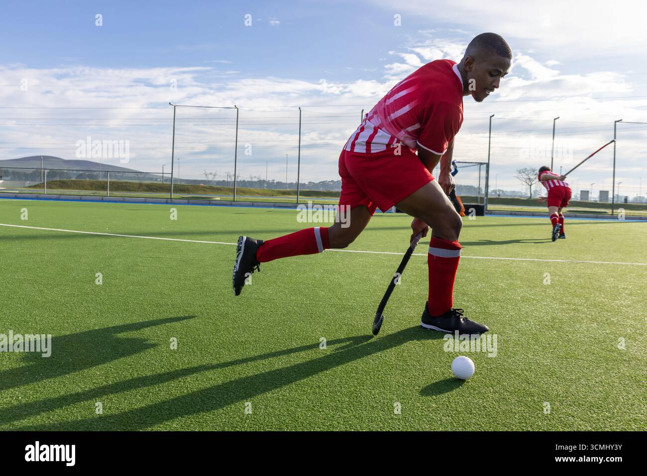 Divers coéquipiers en maillots penchés en avant contrôlant la balle avec un bâton de hockey sur gazon Banque D'Images