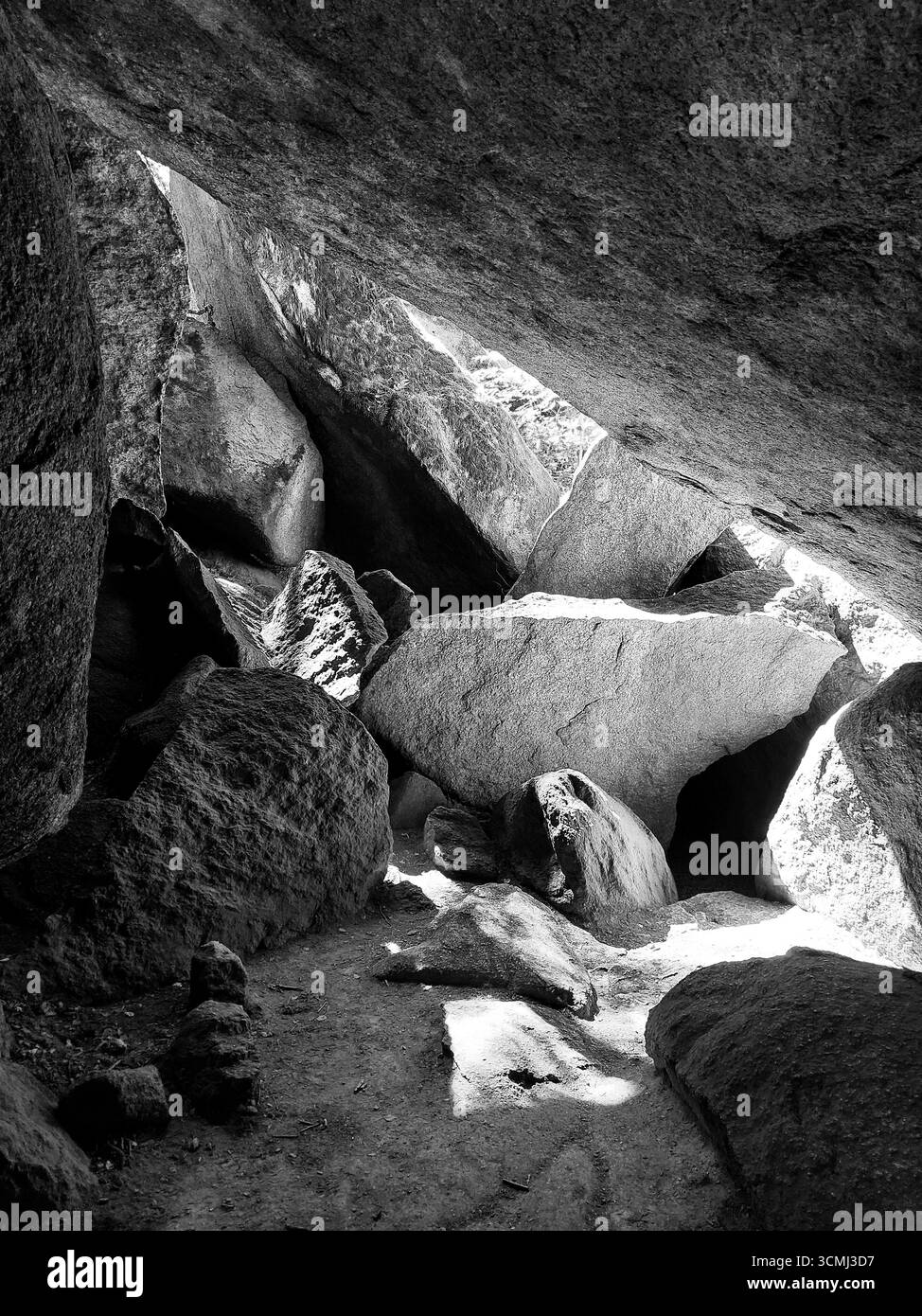 Grotte rocheuse avec de grands rochers et lumière naturelle créant le contraste dans la formation de pierre accidentée. Banque D'Images