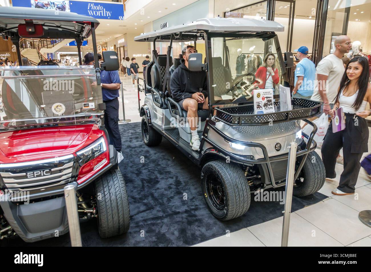 Aventura Mall Miami Florida, à l'intérieur des magasins, affichage de voiturette de golf électrique d'icône, plancher de salle d'exposition de véhicule, modèles en argent rouge garés, homme assis Banque D'Images