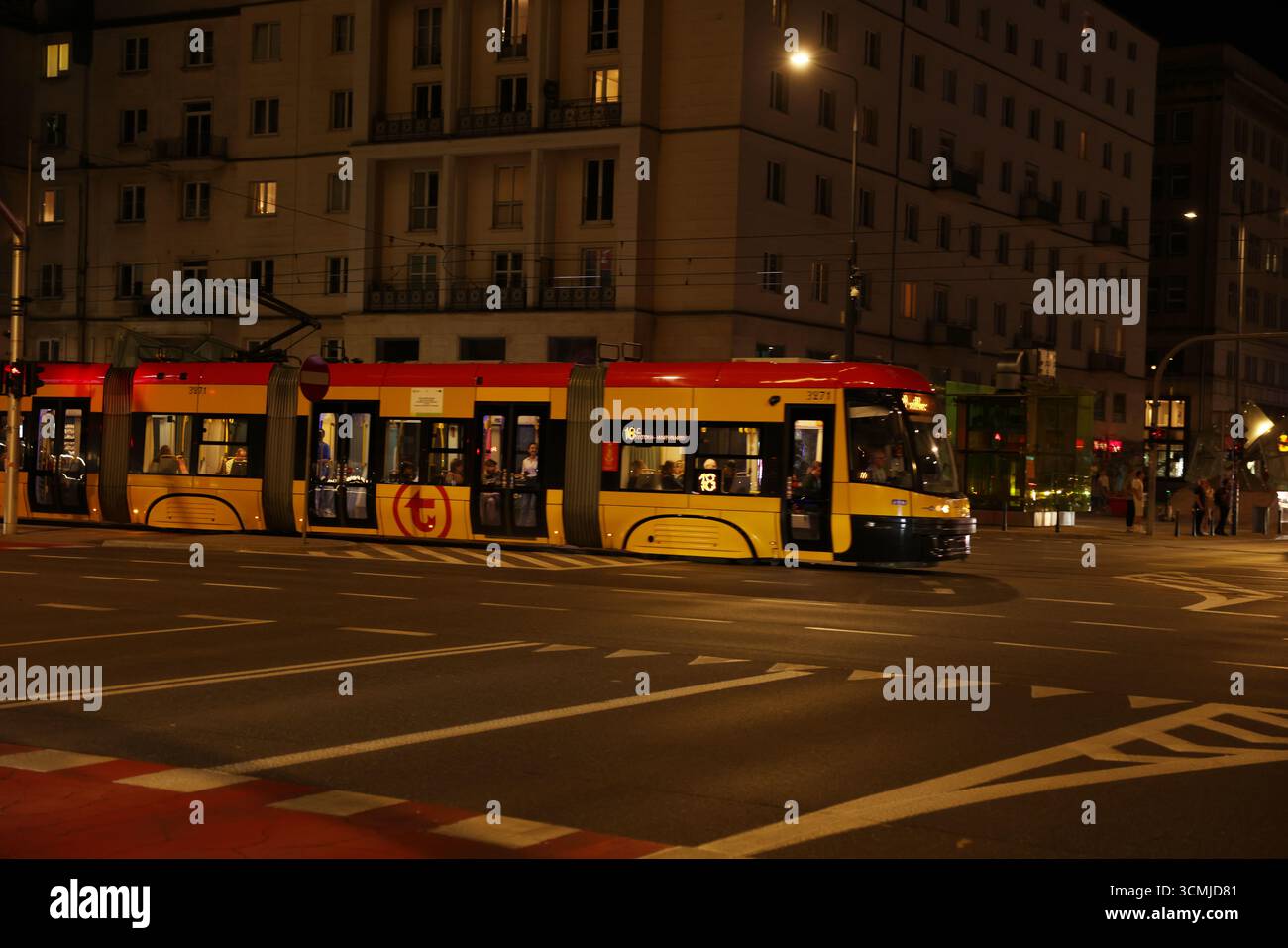 Tramway de Varsovie à l'intersection de nuit avec les rues de la ville incandescentes Banque D'Images