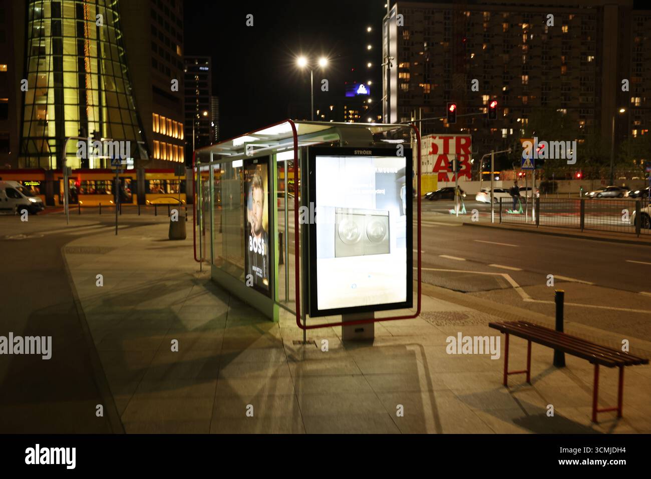 Abri de bus illuminé et panneau d'affichage dans la scène de rue nocturne de Varsovie Banque D'Images
