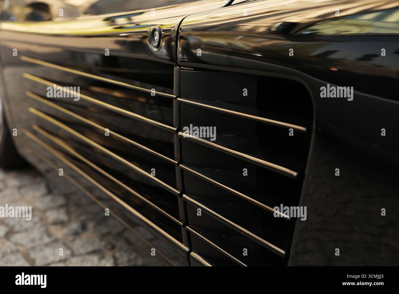 Prises d'air latérales en gros plan sur supercar noire, lignes graphiques et reflets dorés, Varsovie Banque D'Images
