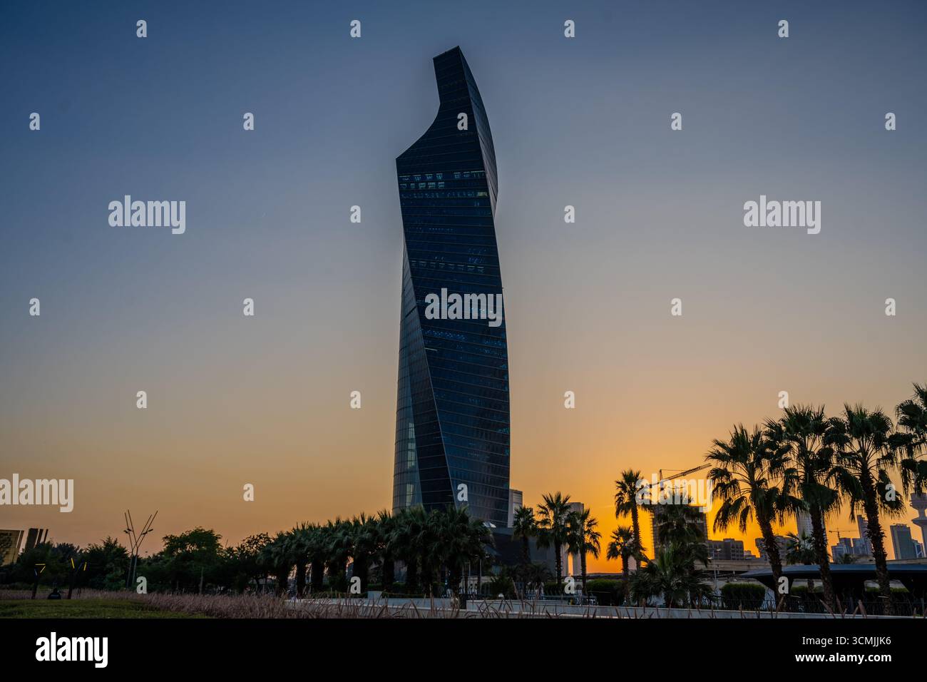 Vue d'un gratte-ciel moderne à Koweït City au coucher du soleil avec des palmiers silhouettés au premier plan au parc Al Shaheed. Koweït City, Koweït. Banque D'Images