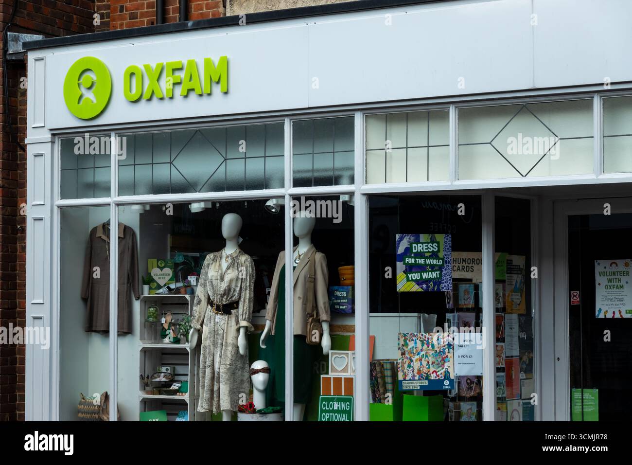 Boutique caritative Oxfam à Bishops Stortford, Hertfordshire, Royaume-Uni. La boutique expose des vêtements et du matériel promotionnel dans sa vitrine. Banque D'Images