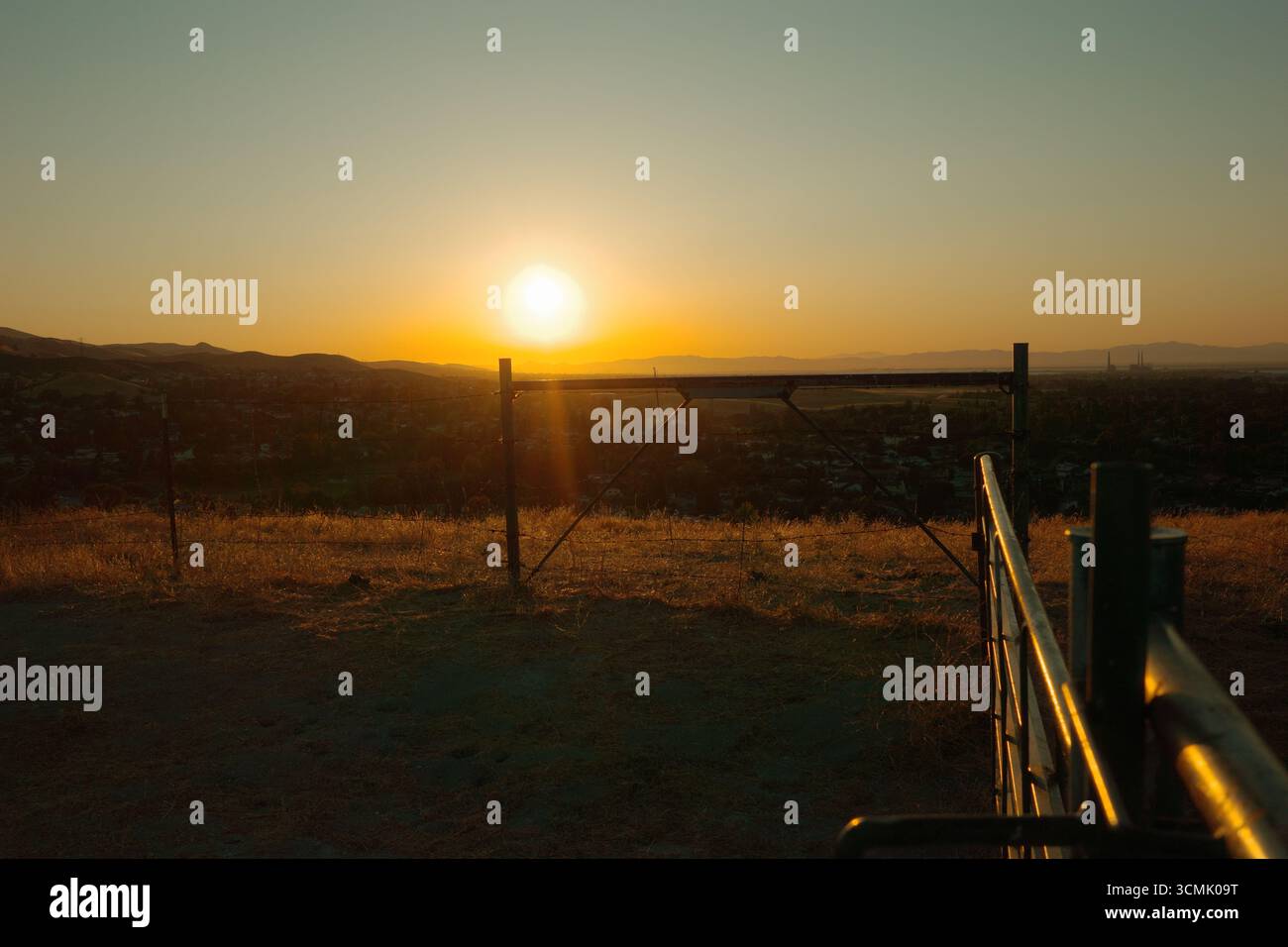 Coucher de soleil doré sur les collines d'Antioch, Californie, avec une clôture rustique et des barbelés au premier plan. Prise près de Contra Loma et East Bay Banque D'Images