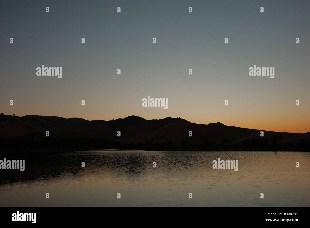 Coucher de soleil sur le réservoir Contra Loma à Antioch, Californie, qui fait partie du quartier du parc régional d'East Bay. La lumière dorée se reflète sur l'eau. Banque D'Images