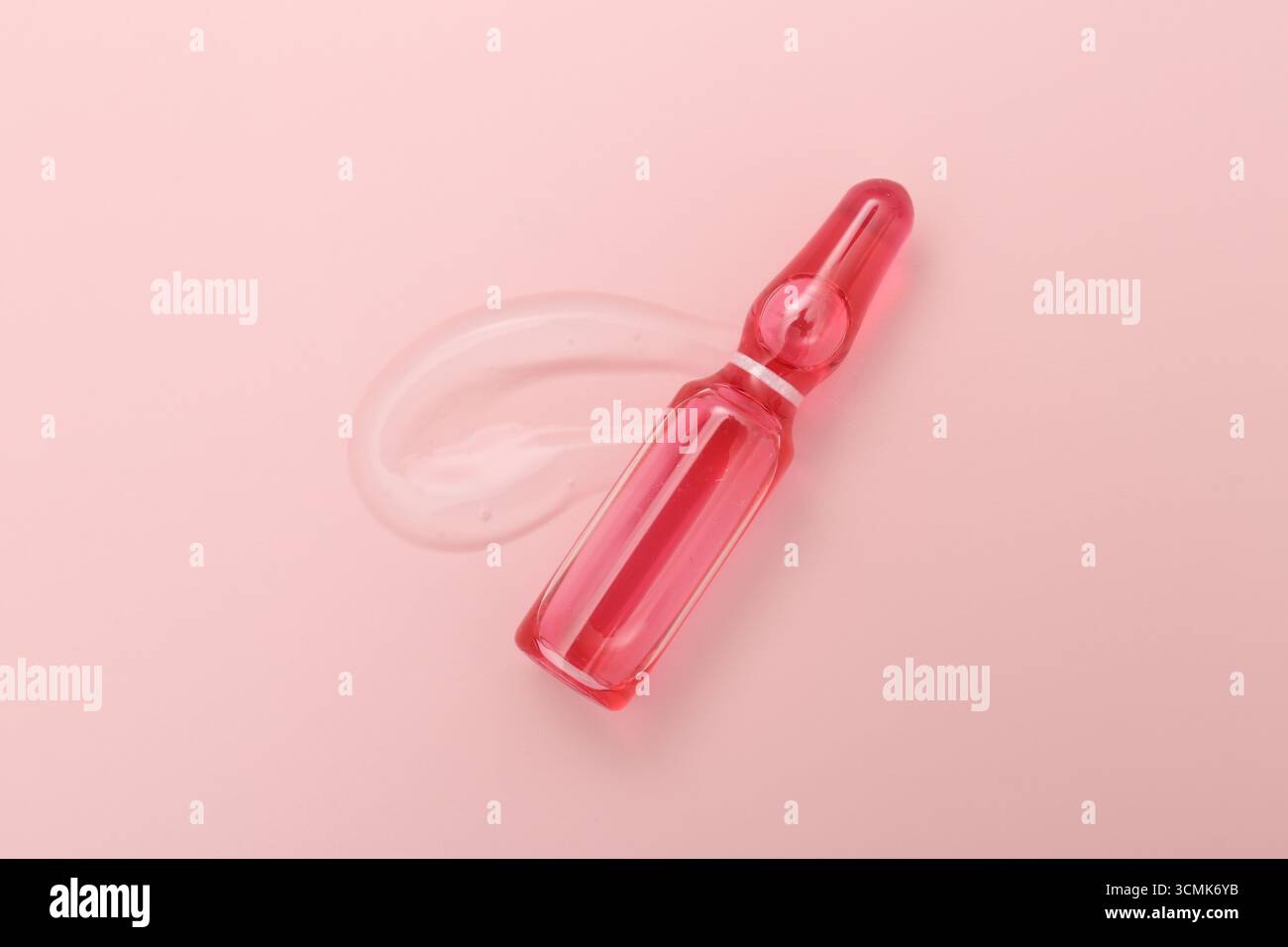 Ampoule en verre avec produit cosmétique sur fond rose, vue de dessus Banque D'Images